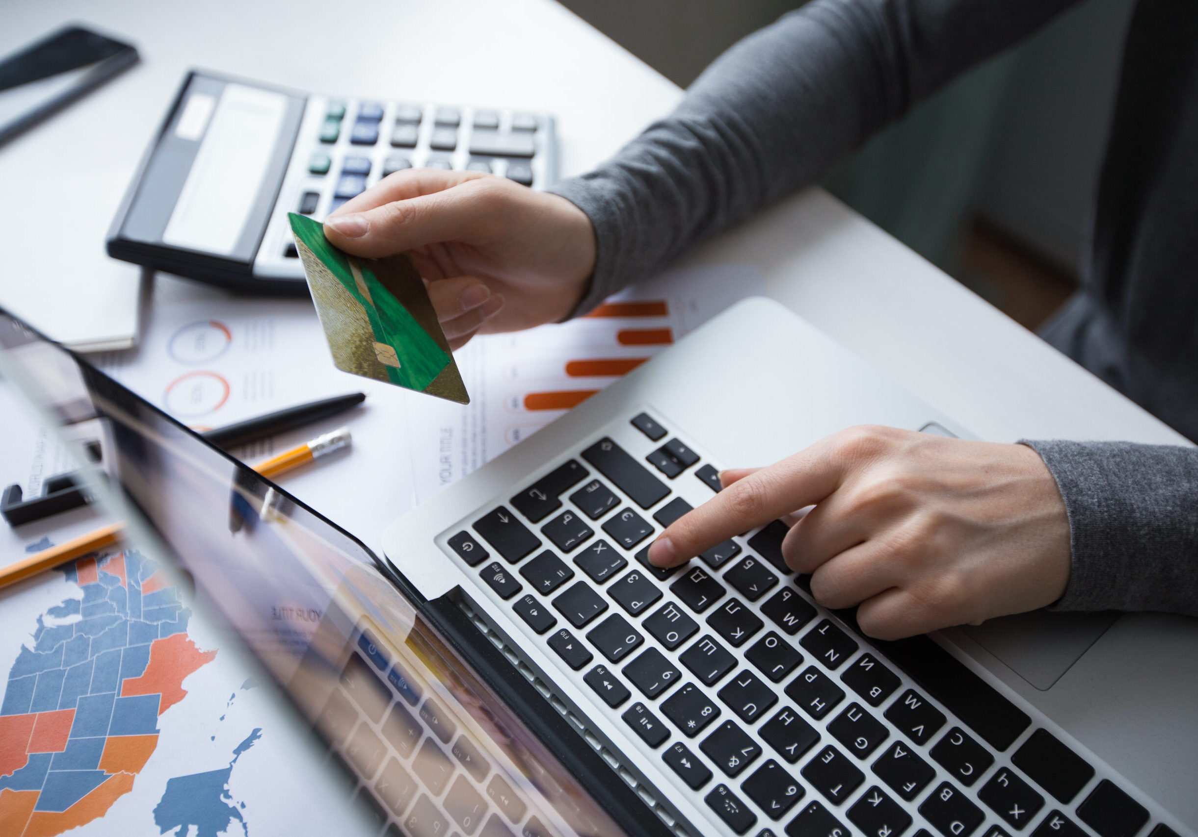 Cropped view of business person working on laptop computer, holding credit card and doing online banking